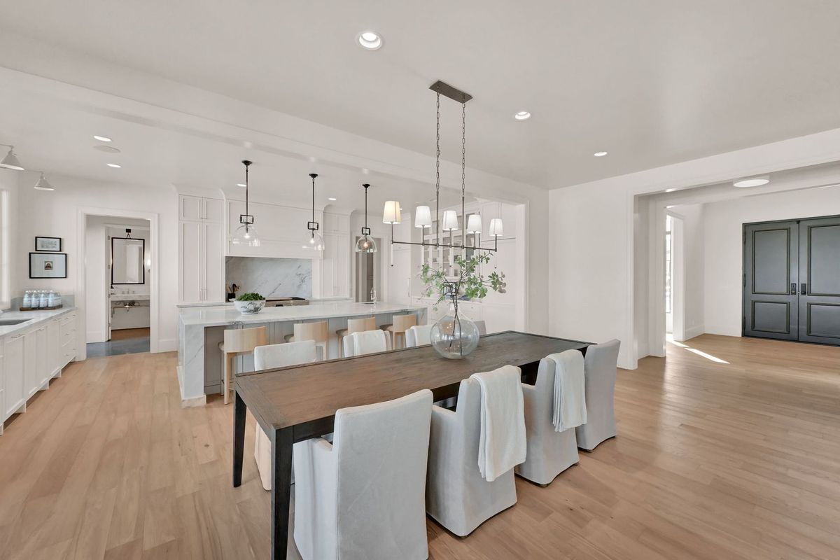 A dining room with a long table and chairs in a house.