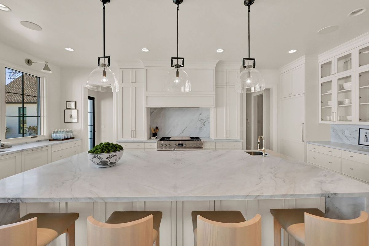 A large kitchen with white cabinets and marble counter tops.