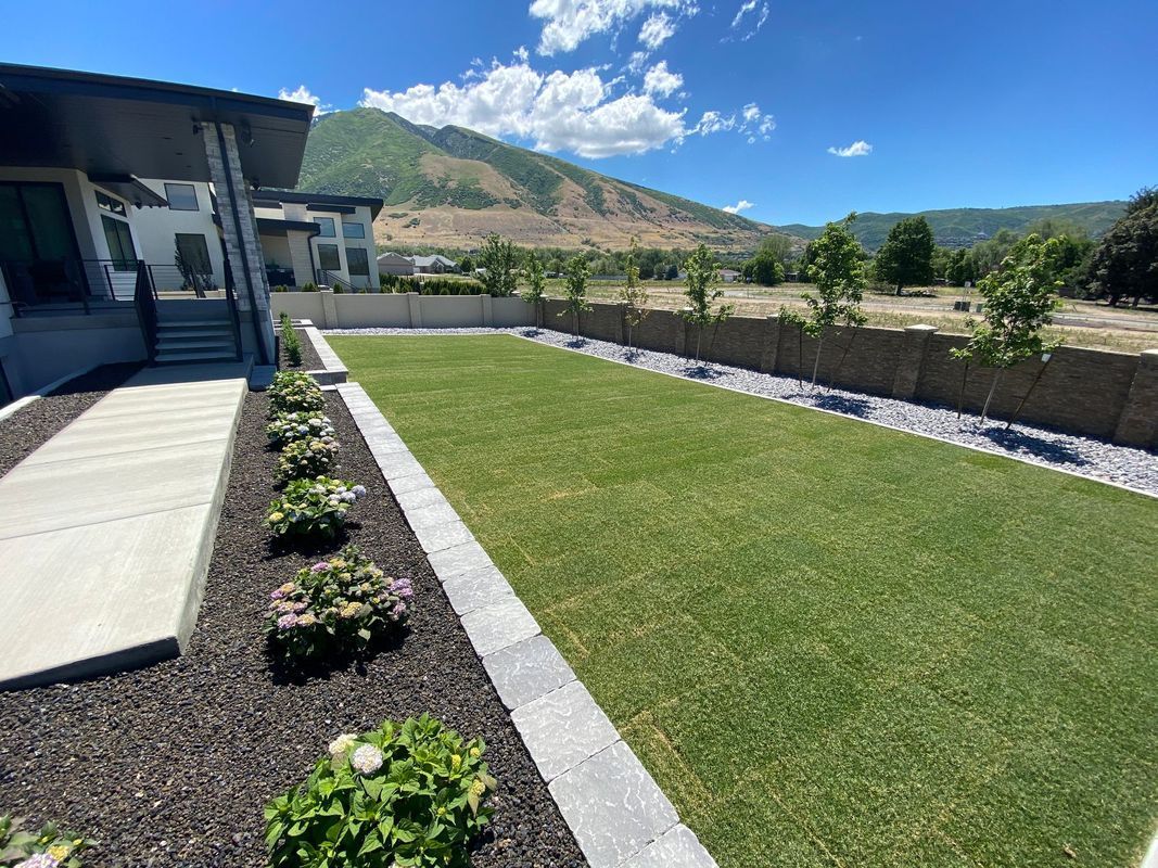A large lawn in front of a house with mountains in the background.