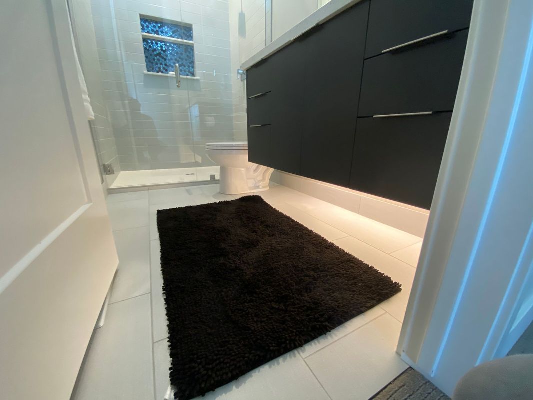 A bathroom with a black rug on the floor.