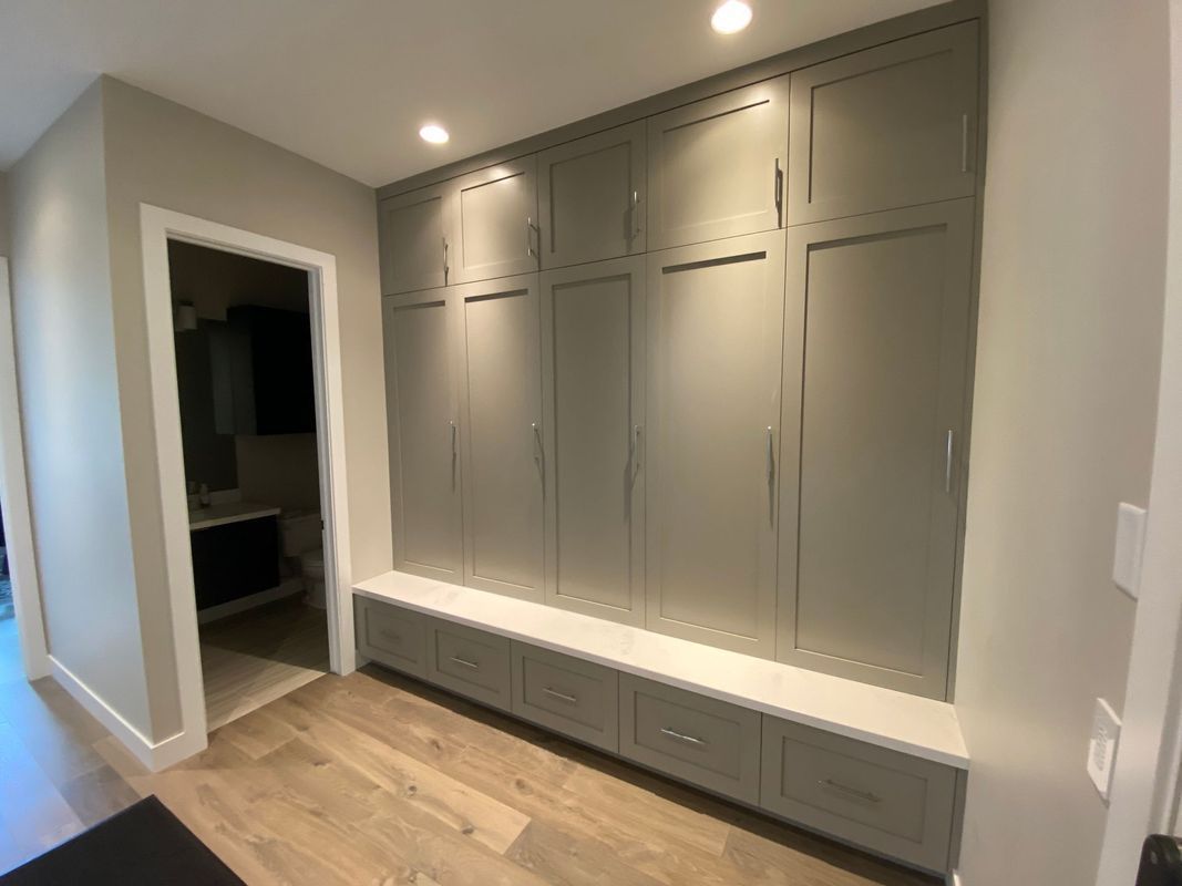 A hallway with lots of cabinets and drawers and a bench.