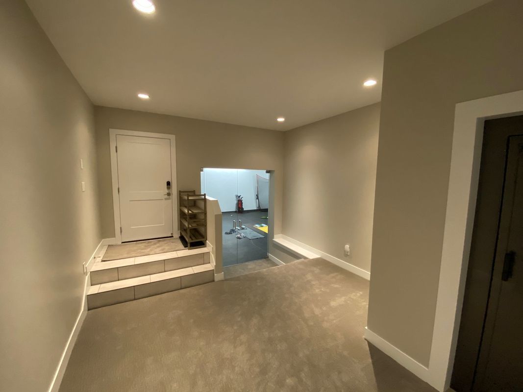 A hallway with a door and stairs leading to a room.