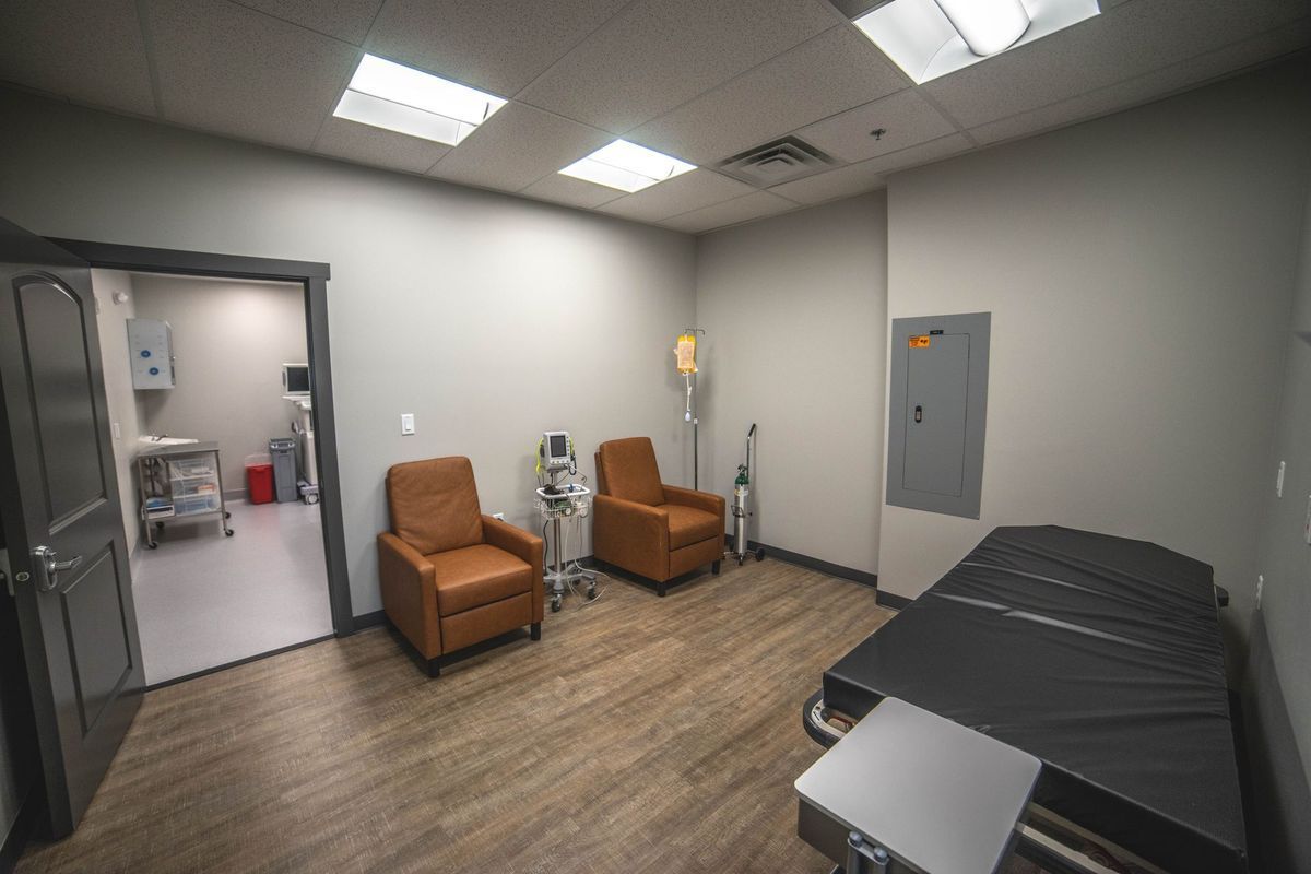 A room with two chairs and a bed in it.