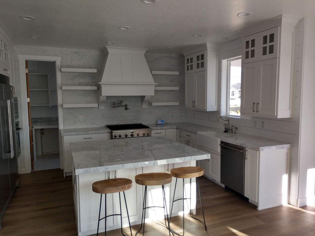 A kitchen with white cabinets and stools and a large island