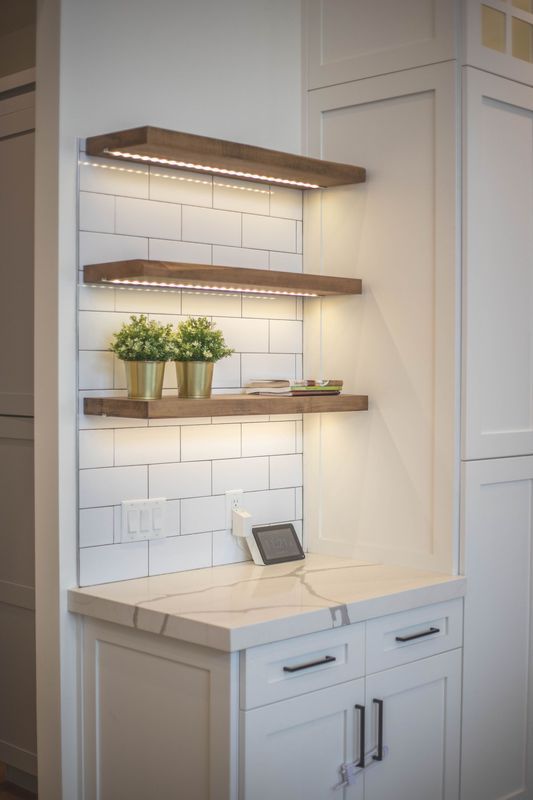 A kitchen with white cabinets and wooden shelves.
