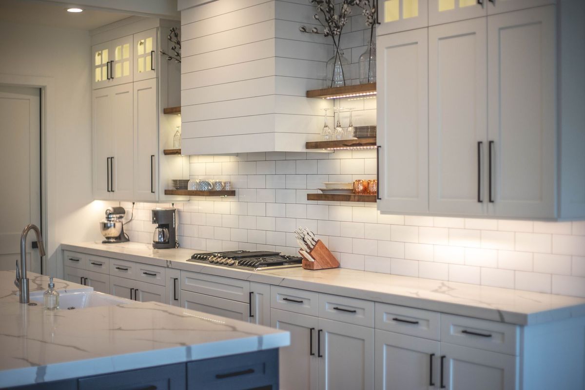 A kitchen with white cabinets and a stove top oven.