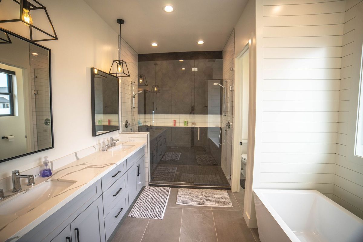 A bathroom with two sinks , a tub , and a walk in shower.