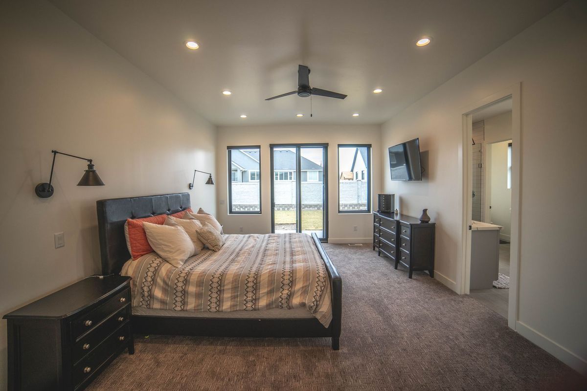 A bedroom with a bed , dresser , nightstand , television and ceiling fan.