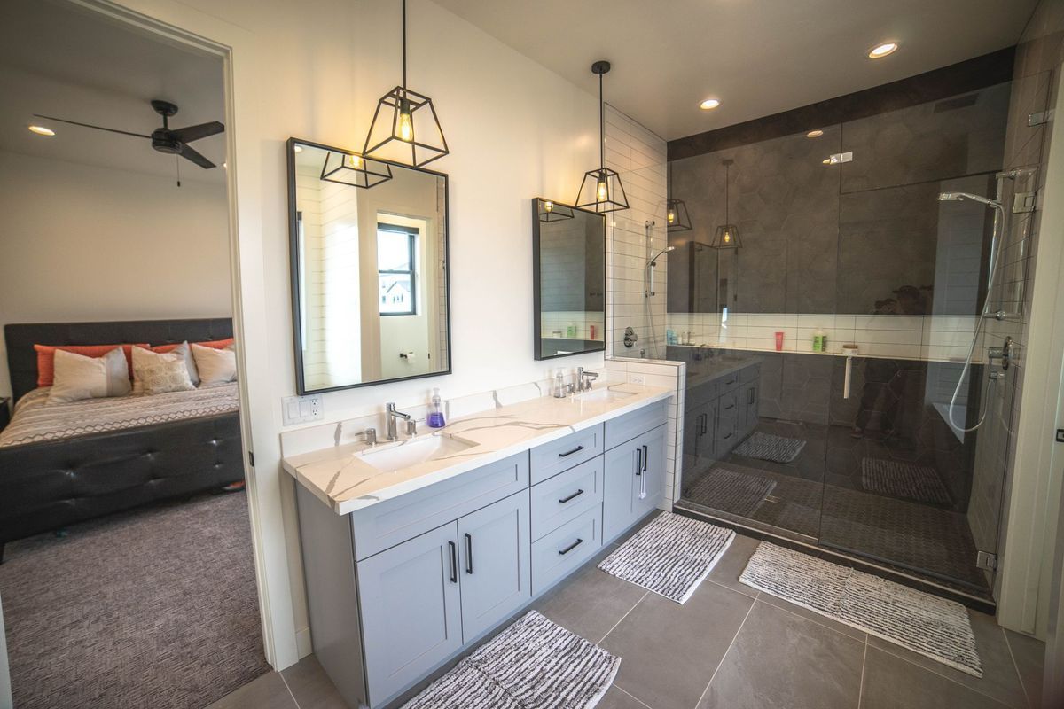 A bathroom with two sinks and a walk in shower.