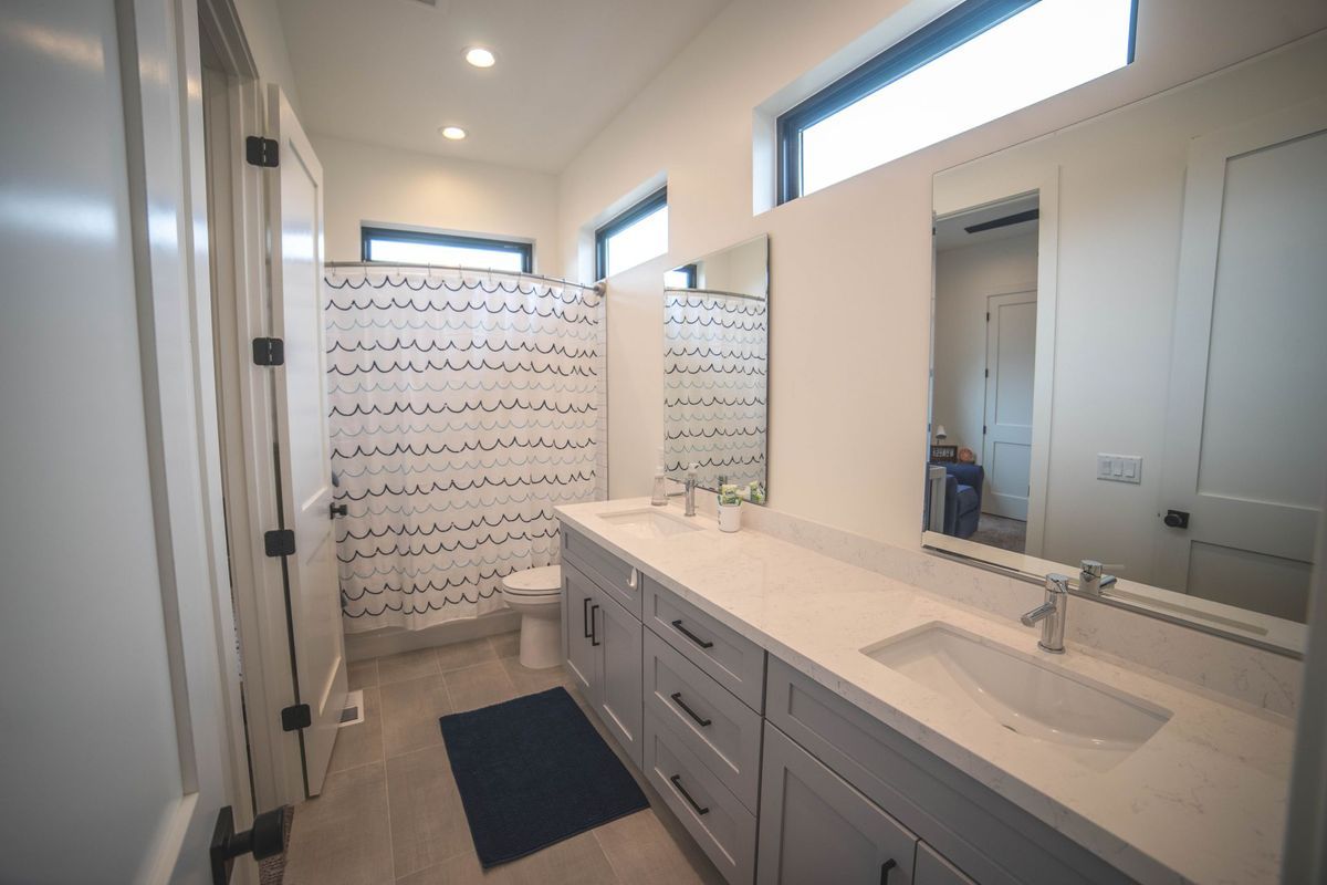 A bathroom with two sinks , a toilet , and a shower stall.