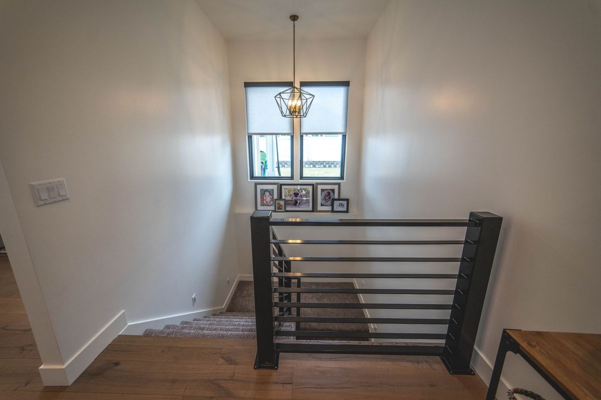 A staircase in a house with a black railing and a window.