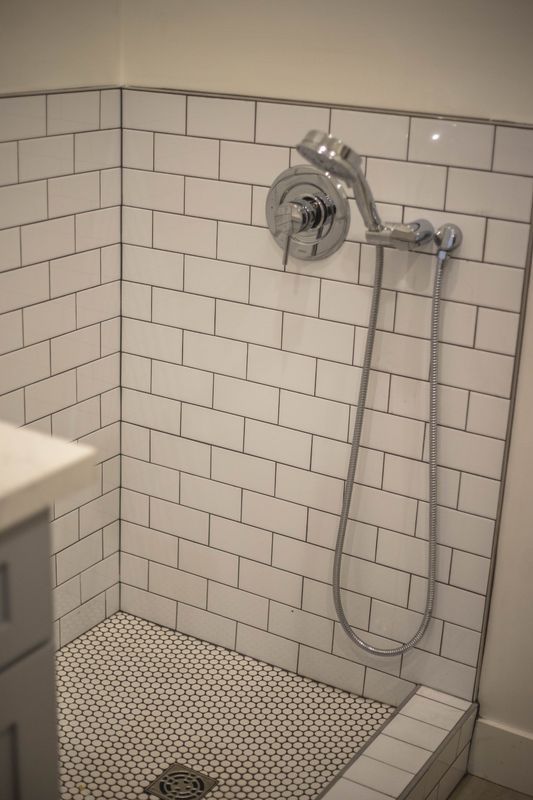 A bathroom with white bricks and a shower head