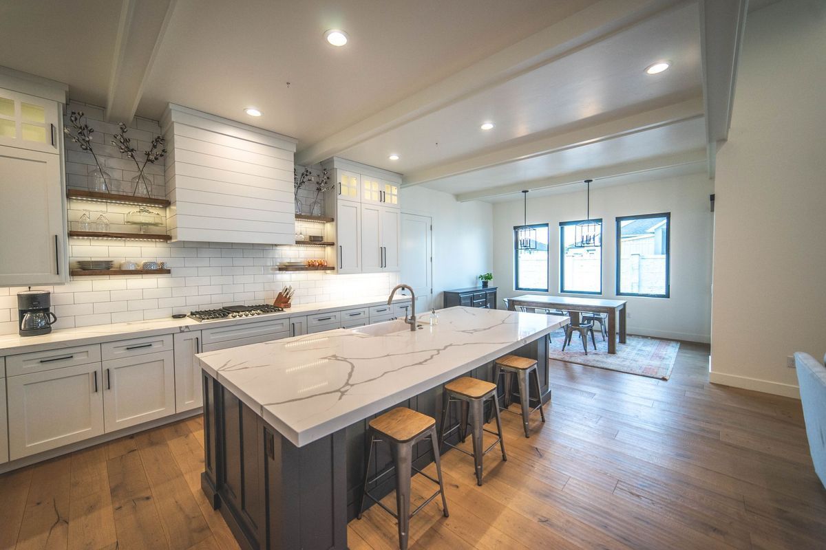 A kitchen with a large island and stools in a house.