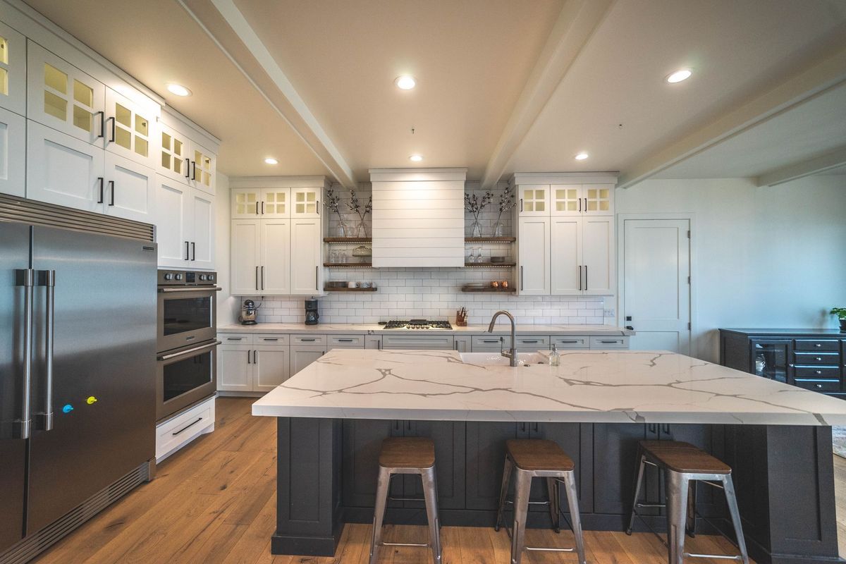 A kitchen with white cabinets , stainless steel appliances , and a large island.