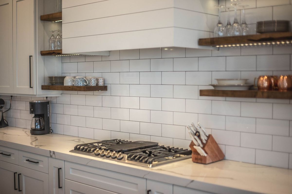 A kitchen with white cabinets and a stove top oven.
