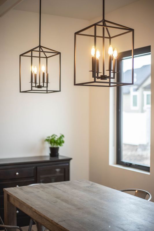 A dining room with a table and chairs and two lanterns hanging from the ceiling