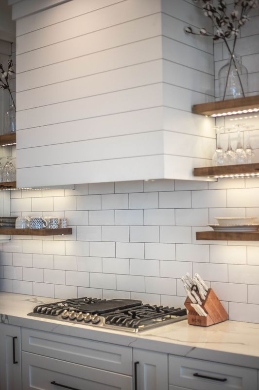A kitchen with white cabinets and a stove top oven.