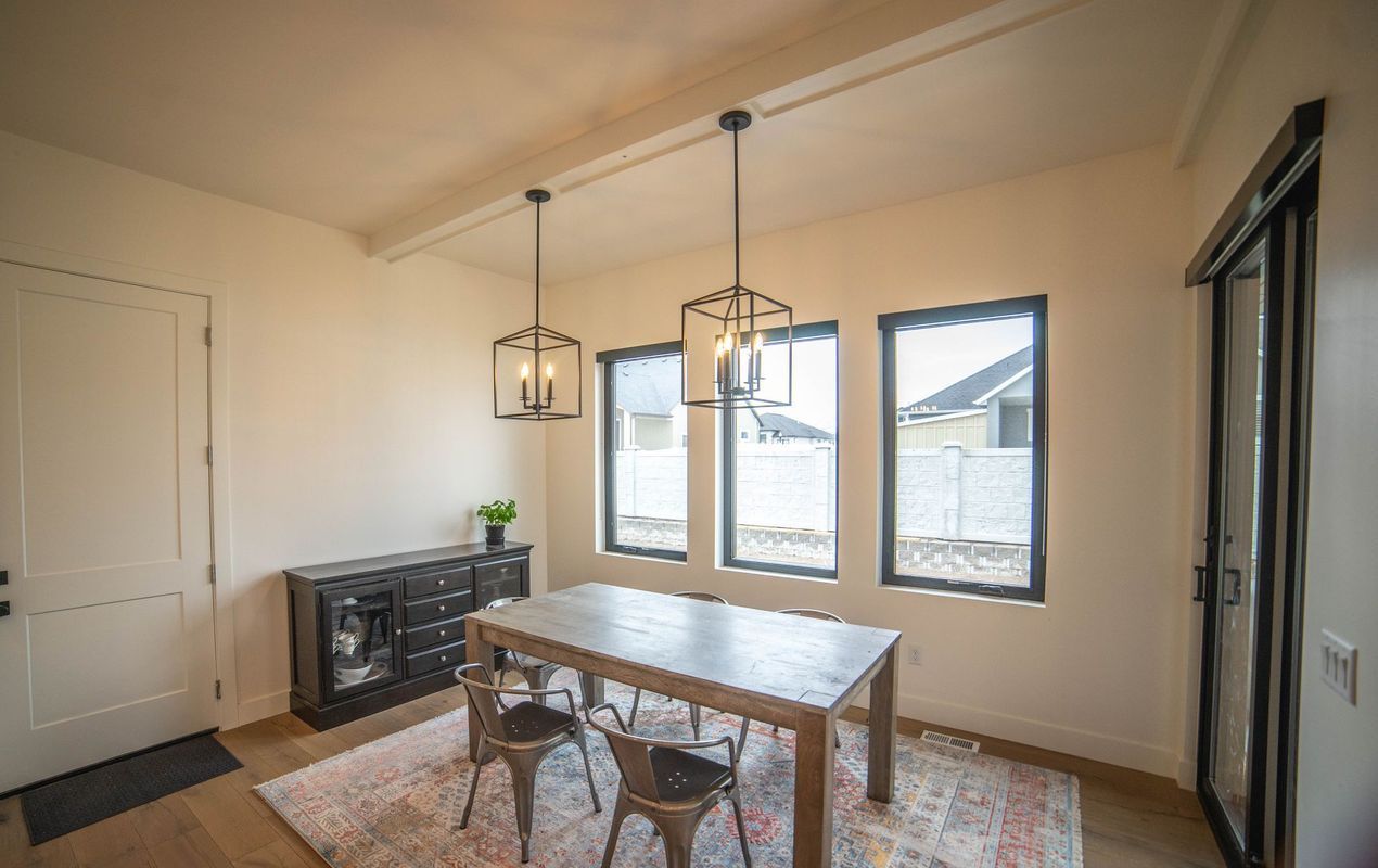 A dining room with a table and chairs and lots of windows.