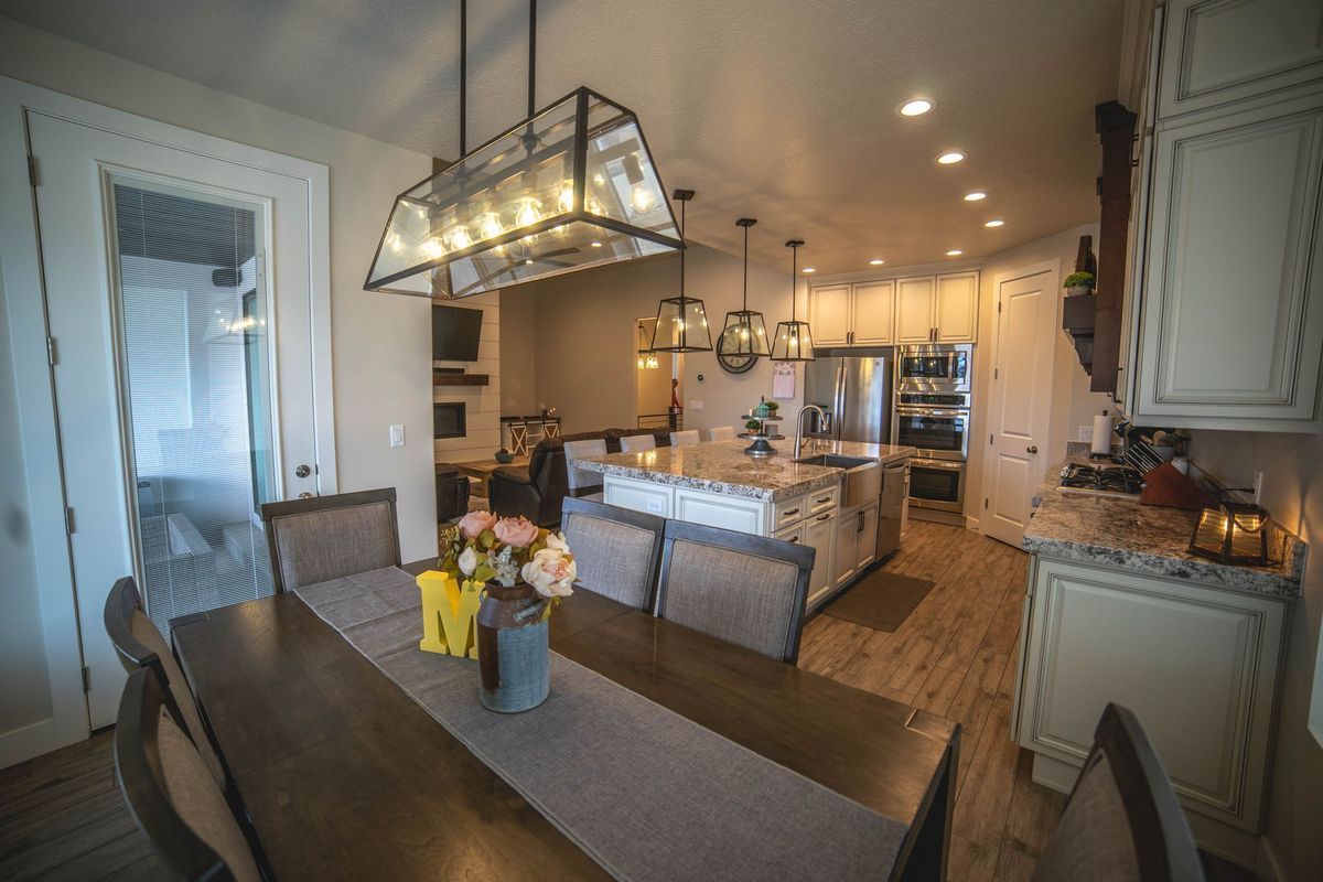 A dining room table with a vase of flowers on it in a kitchen.