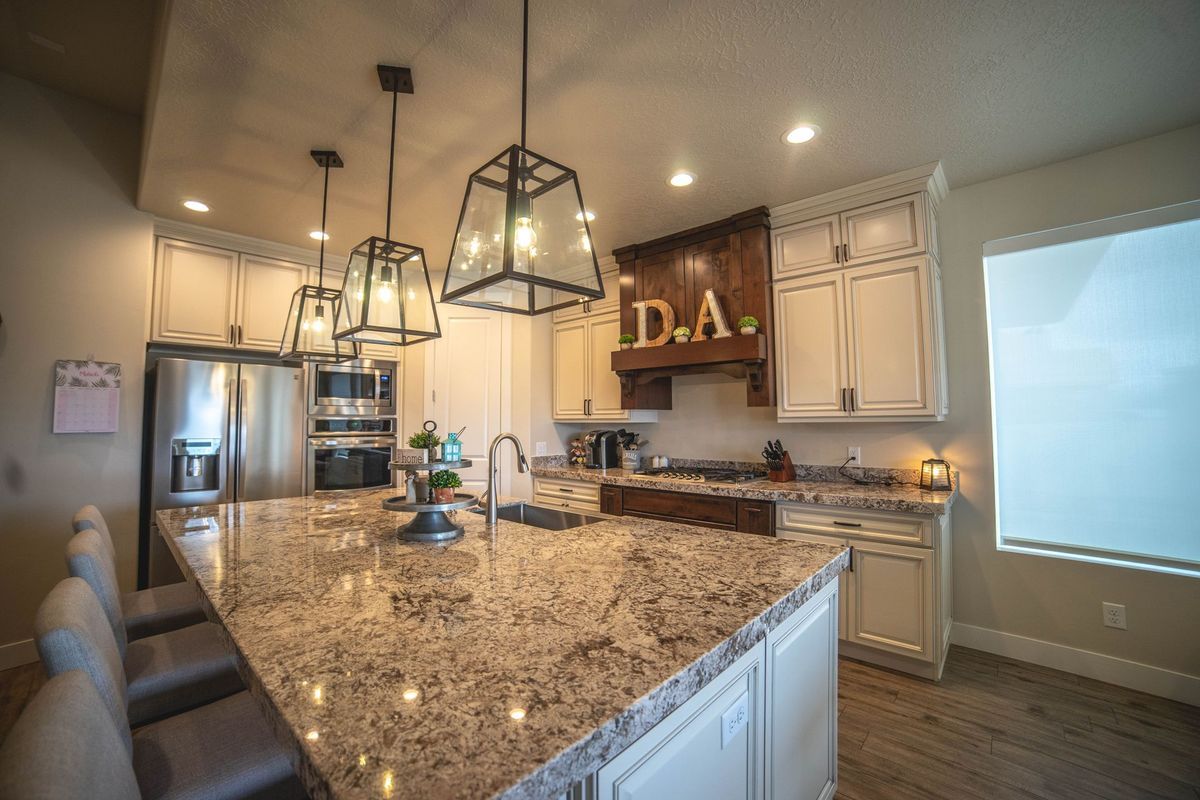 A kitchen with granite counter tops , white cabinets , stainless steel appliances and a large island.