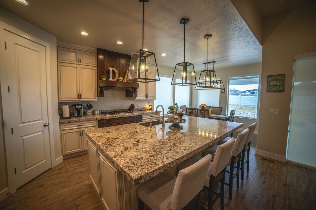A kitchen with granite counter tops , white cabinets , and a large island.