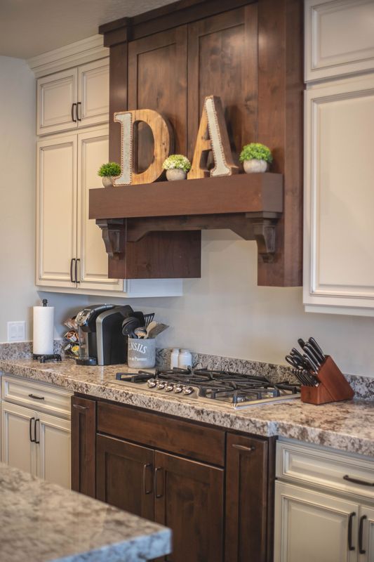 A kitchen with a stove top oven , granite counter tops , and wooden cabinets.