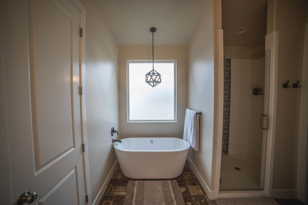 A bathroom with a tub , shower and window.