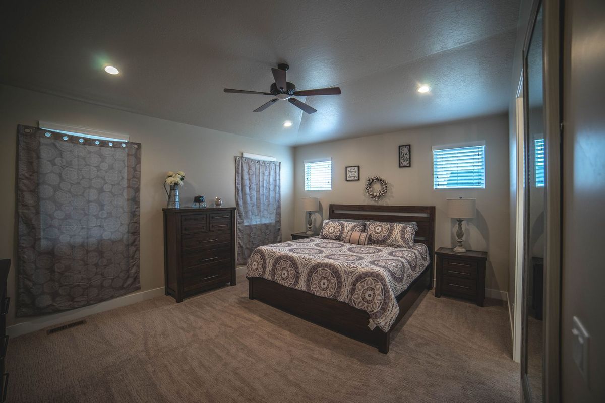 A bedroom with a king size bed and a ceiling fan.