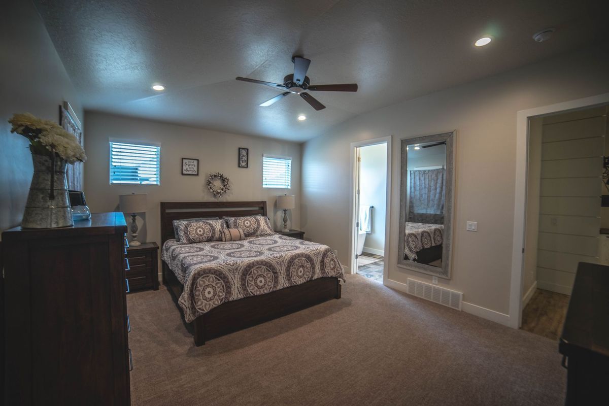 A bedroom with a large bed and a ceiling fan.