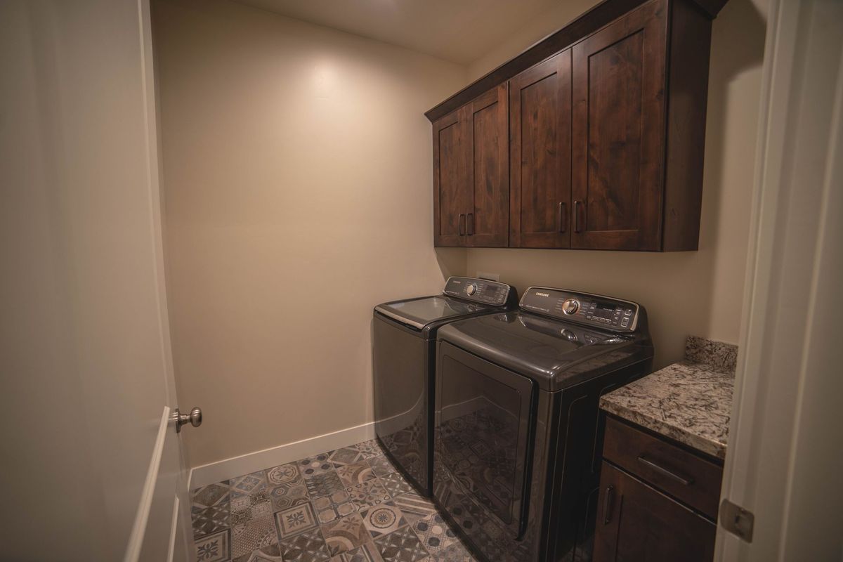 A laundry room with a washer and dryer and wooden cabinets.