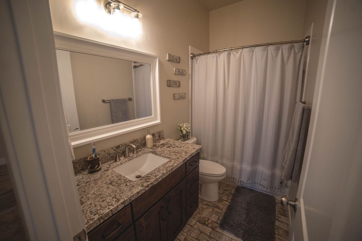 A bathroom with a sink , toilet , shower and mirror.