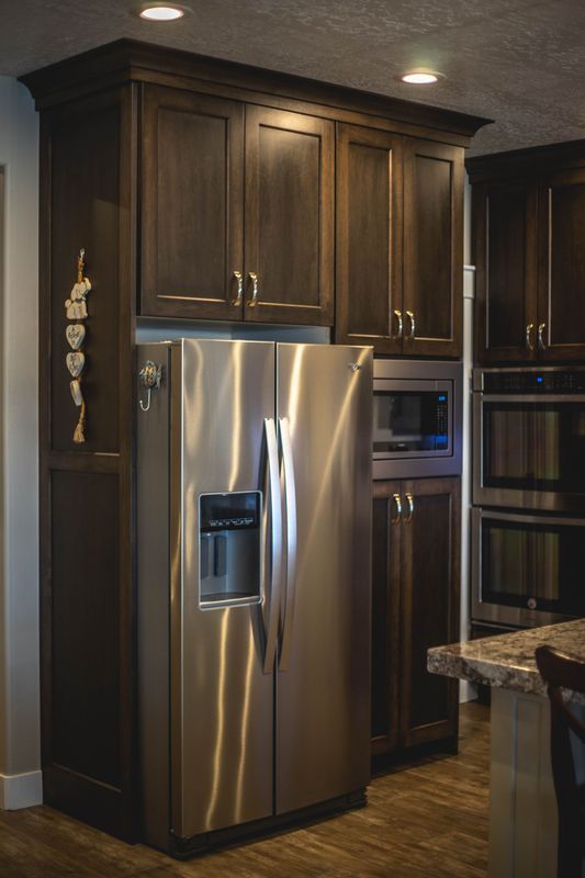 A stainless steel refrigerator in a kitchen with wooden cabinets.