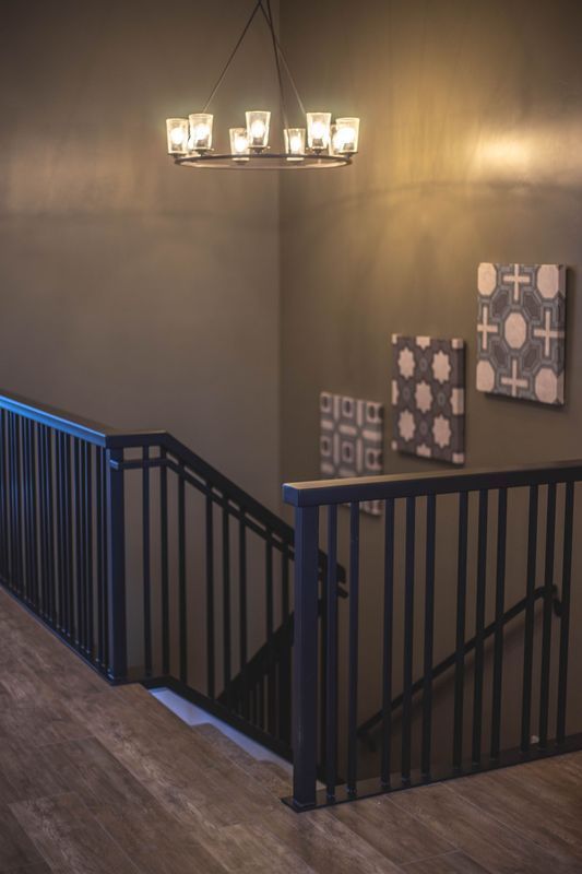 A staircase with a black railing and a chandelier hanging from the ceiling.