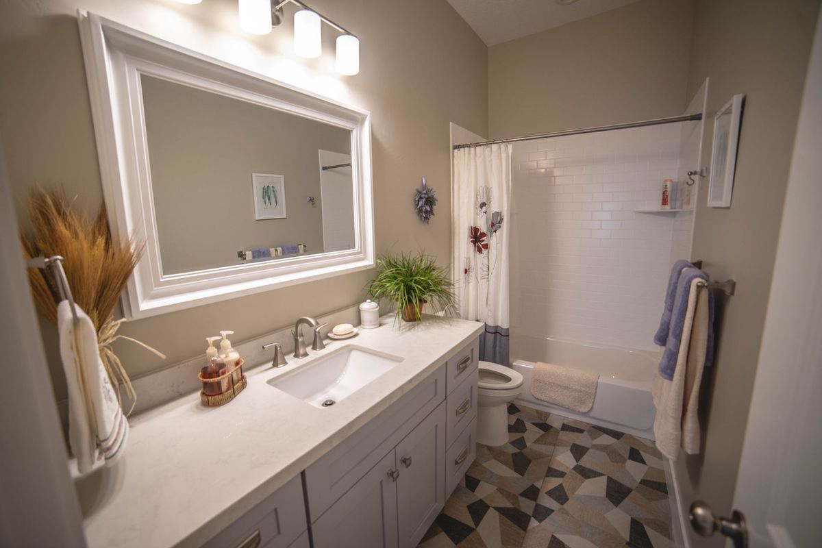 A bathroom with a sink , mirror , toilet and shower.