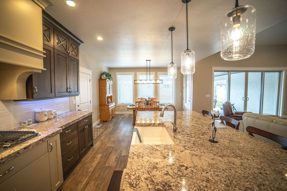 A kitchen with granite counter tops , cabinets , a sink and a dining room in the background.