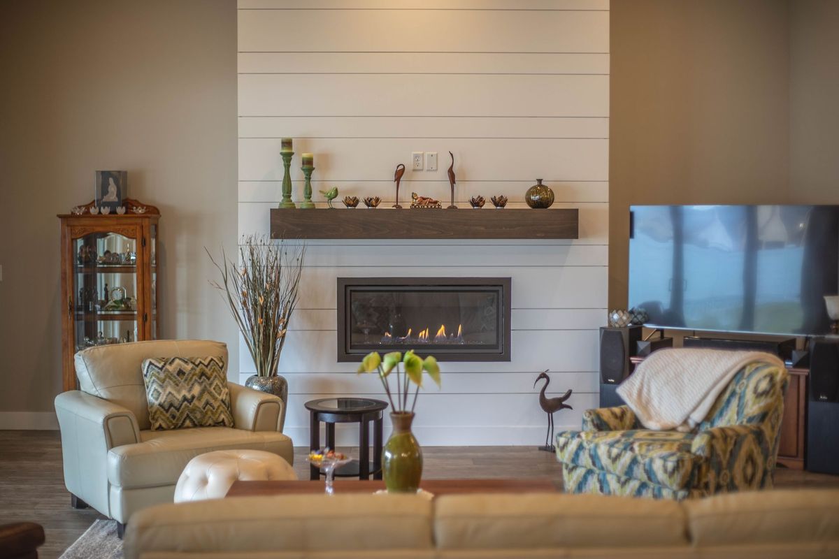 A living room with a fireplace , couch , chairs and television.