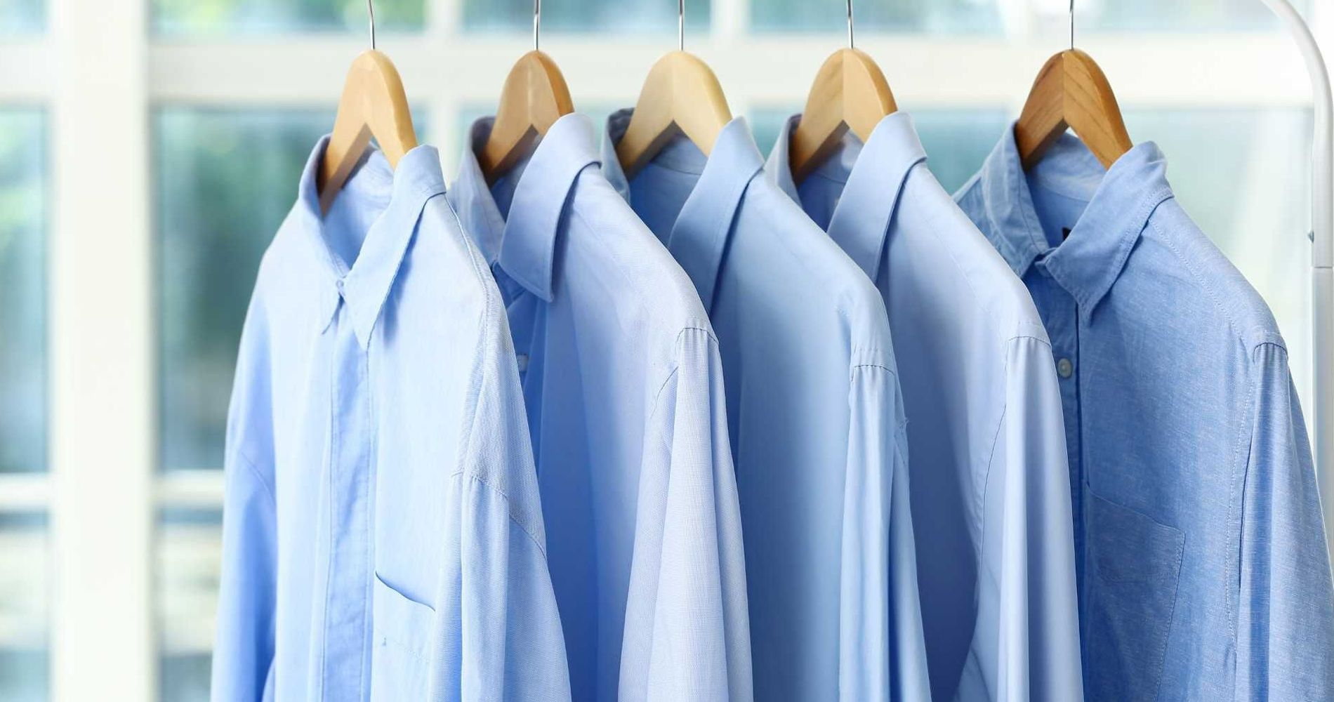 A row of blue shirts hanging on a rack.