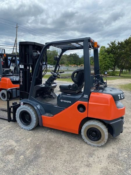 Orange and gray Toyota forklift outdoors under a cloudy sky.