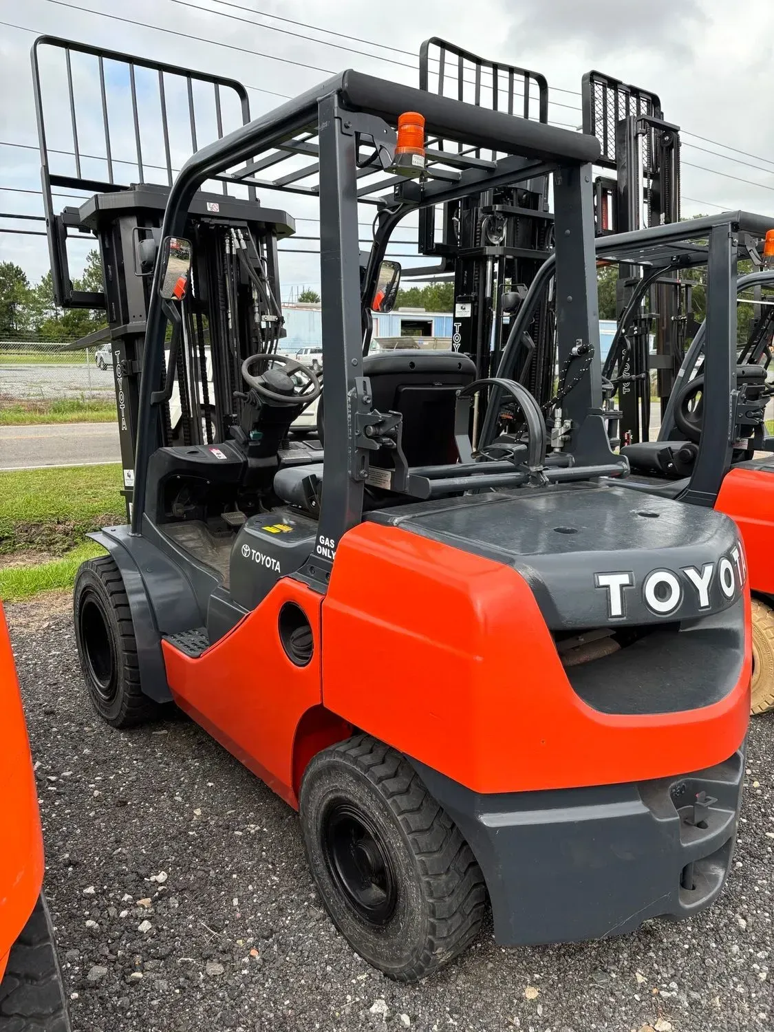 Red and gray Toyota forklift on gravel.