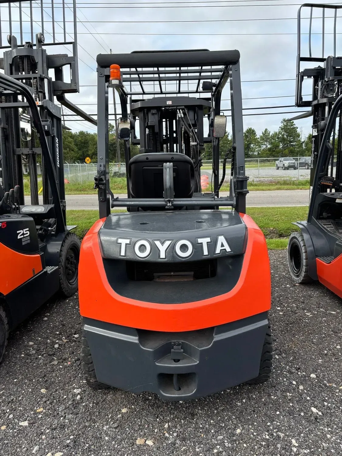 Orange Toyota forklift, front view, outdoors on gravel.