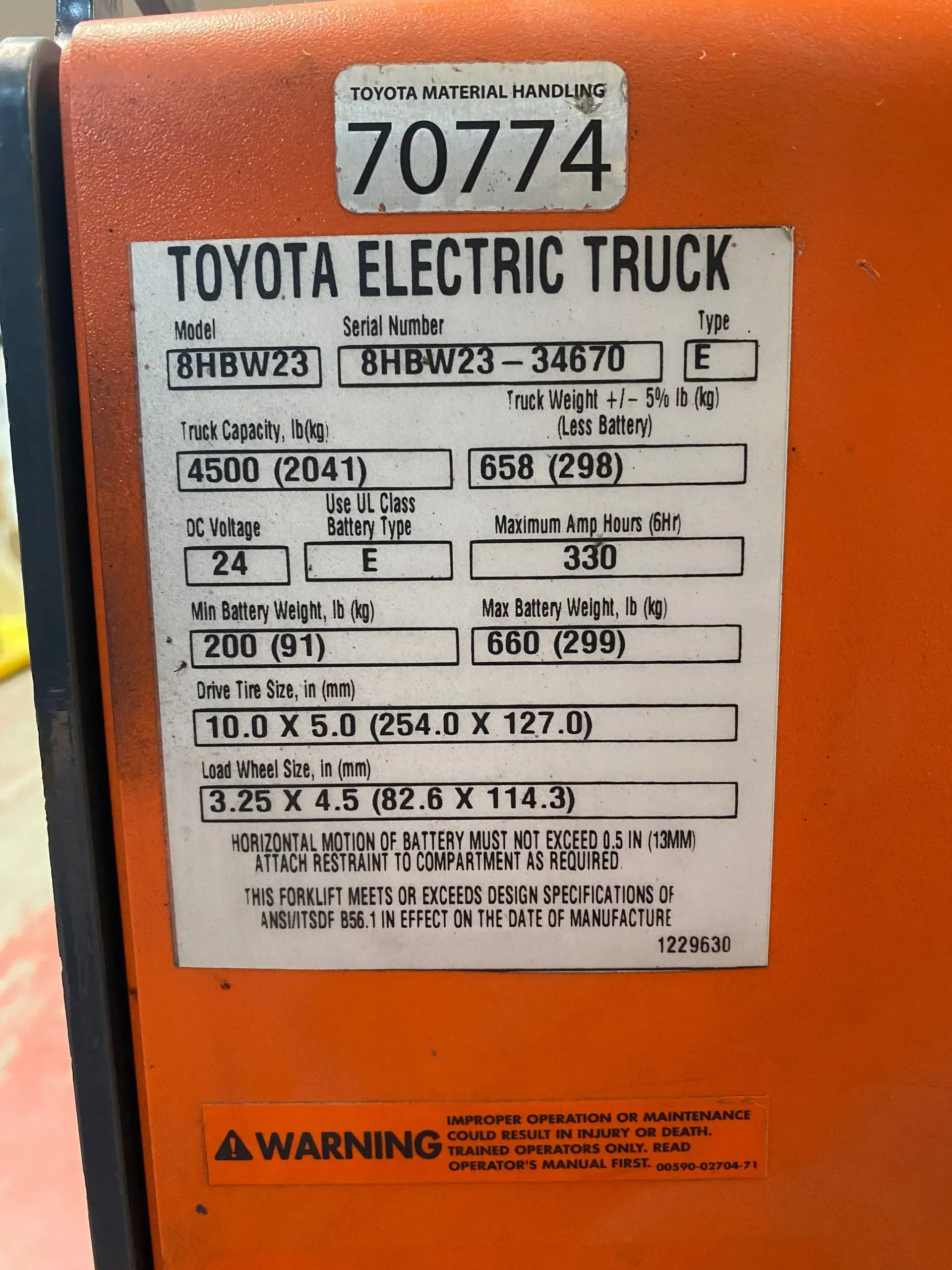 Close-up of an orange Toyota electric truck label with text and numbers, including a warning.
