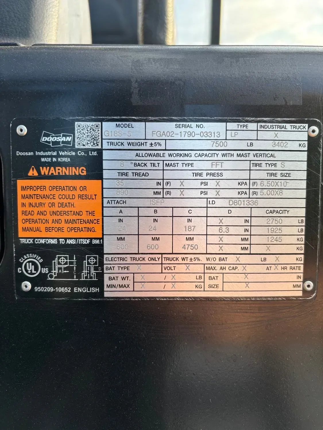 Data plate on a black object, with white text, detailing electrical specifications, and warnings.