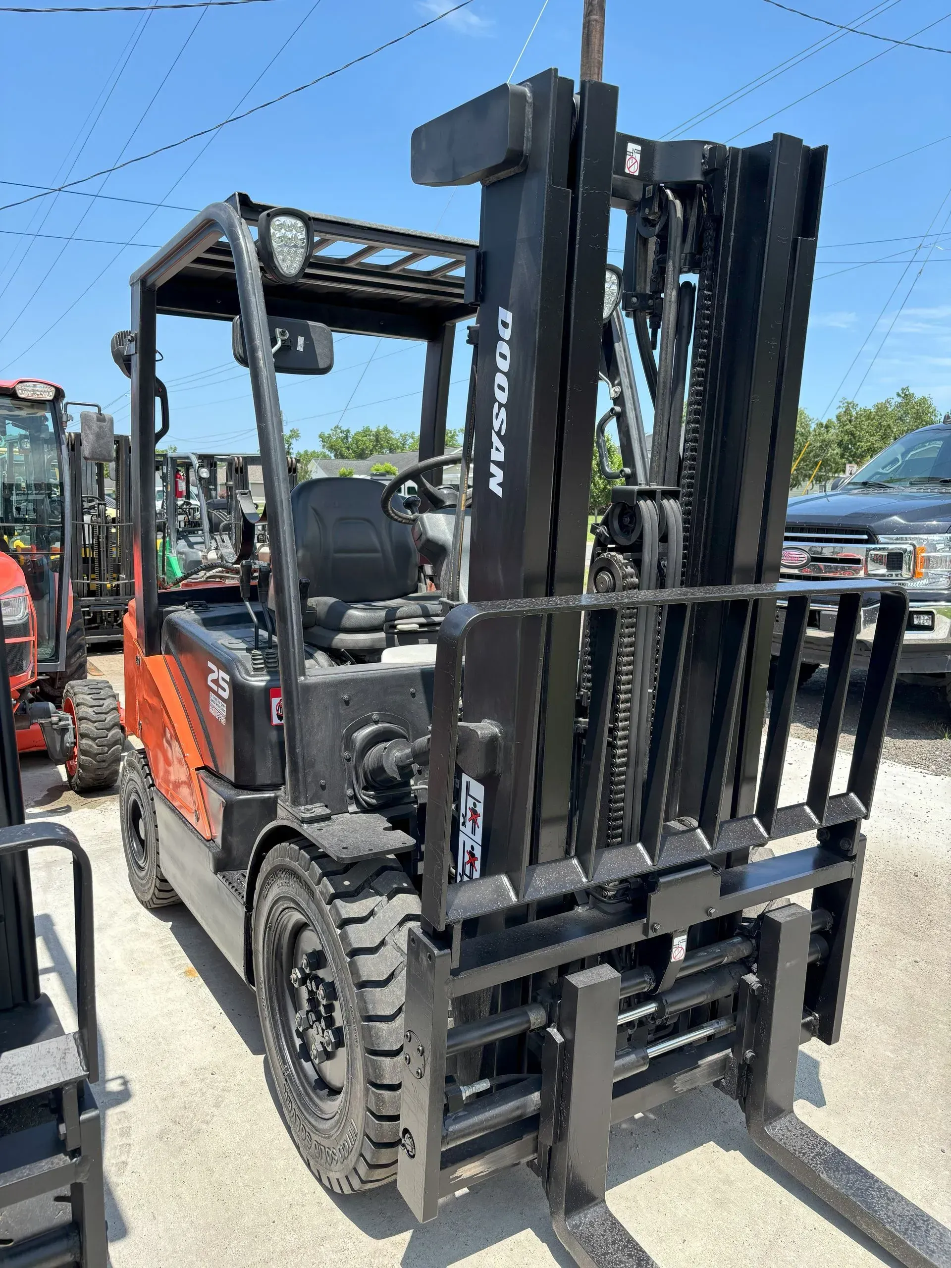 Orange and black forklift outdoors with forks lowered.
