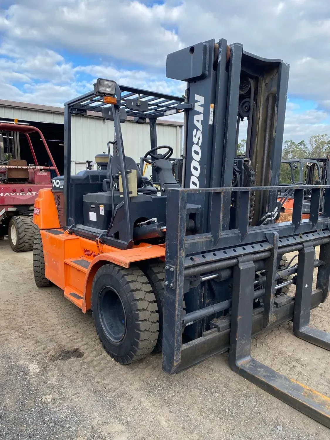 Orange and black Doosan forklift outdoors on gravel.