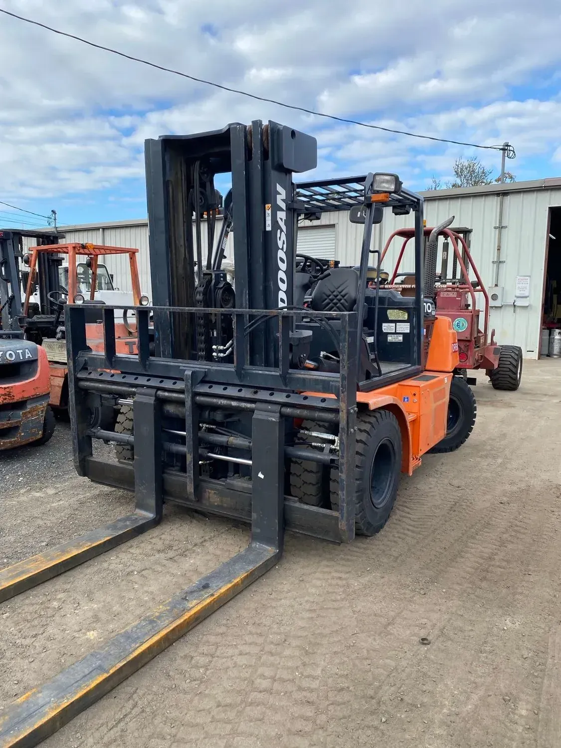 Orange and black Doosan forklift parked outdoors.