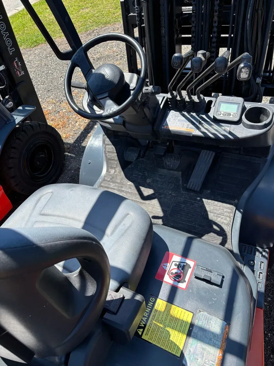 Interior of a forklift showing the seat, steering wheel, control panel, and other mechanisms.