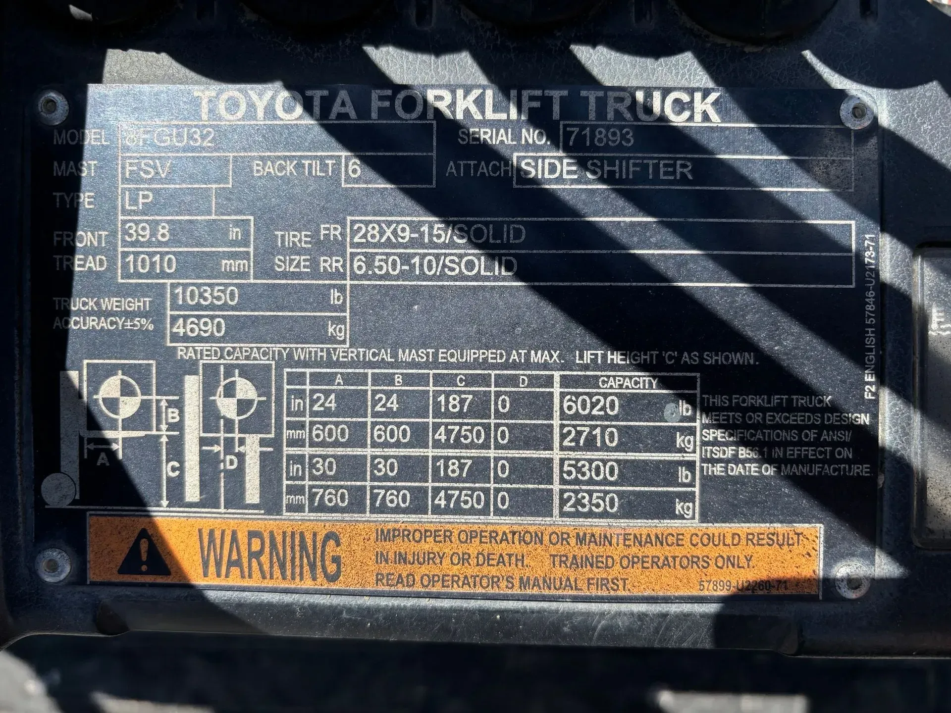 Forklift truck data plate with model, serial number, tire size, and weight capacity information.