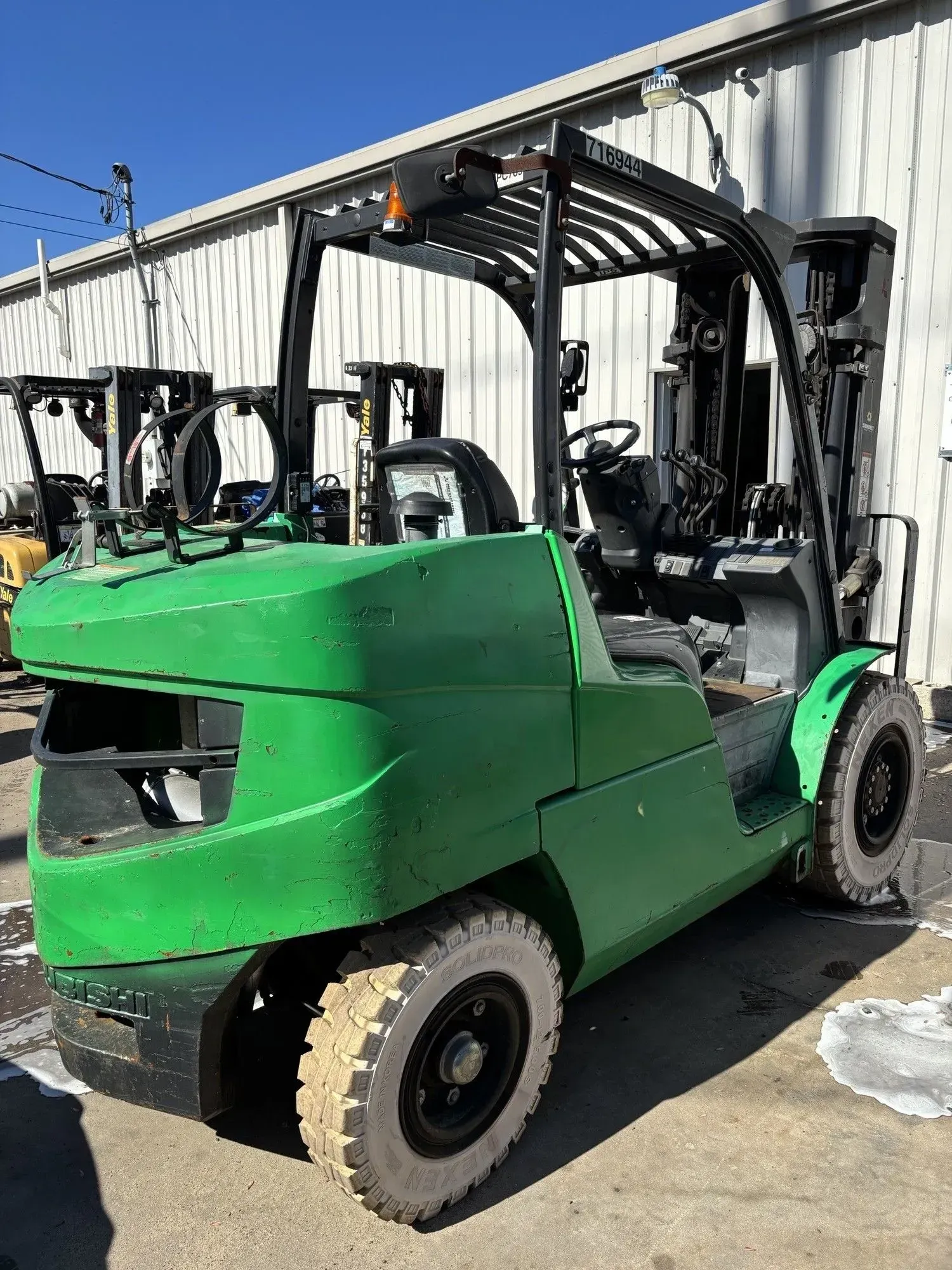 Green forklift parked outside a building.