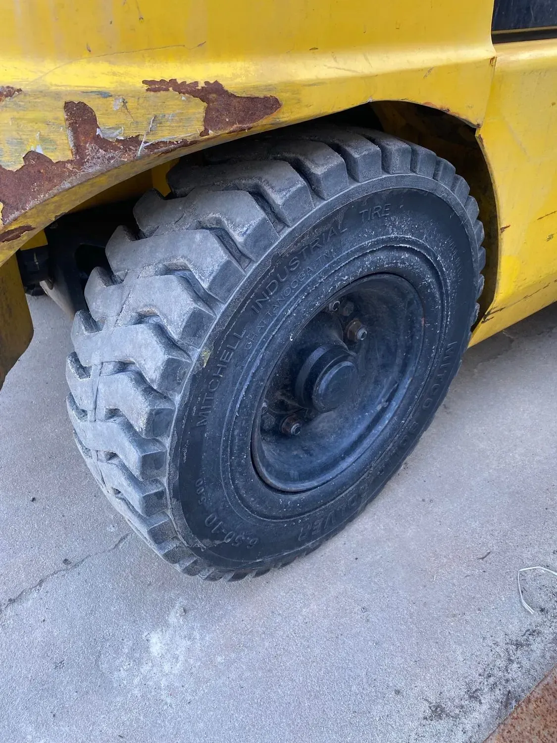 Yellow forklift tire on a concrete surface, close-up view.