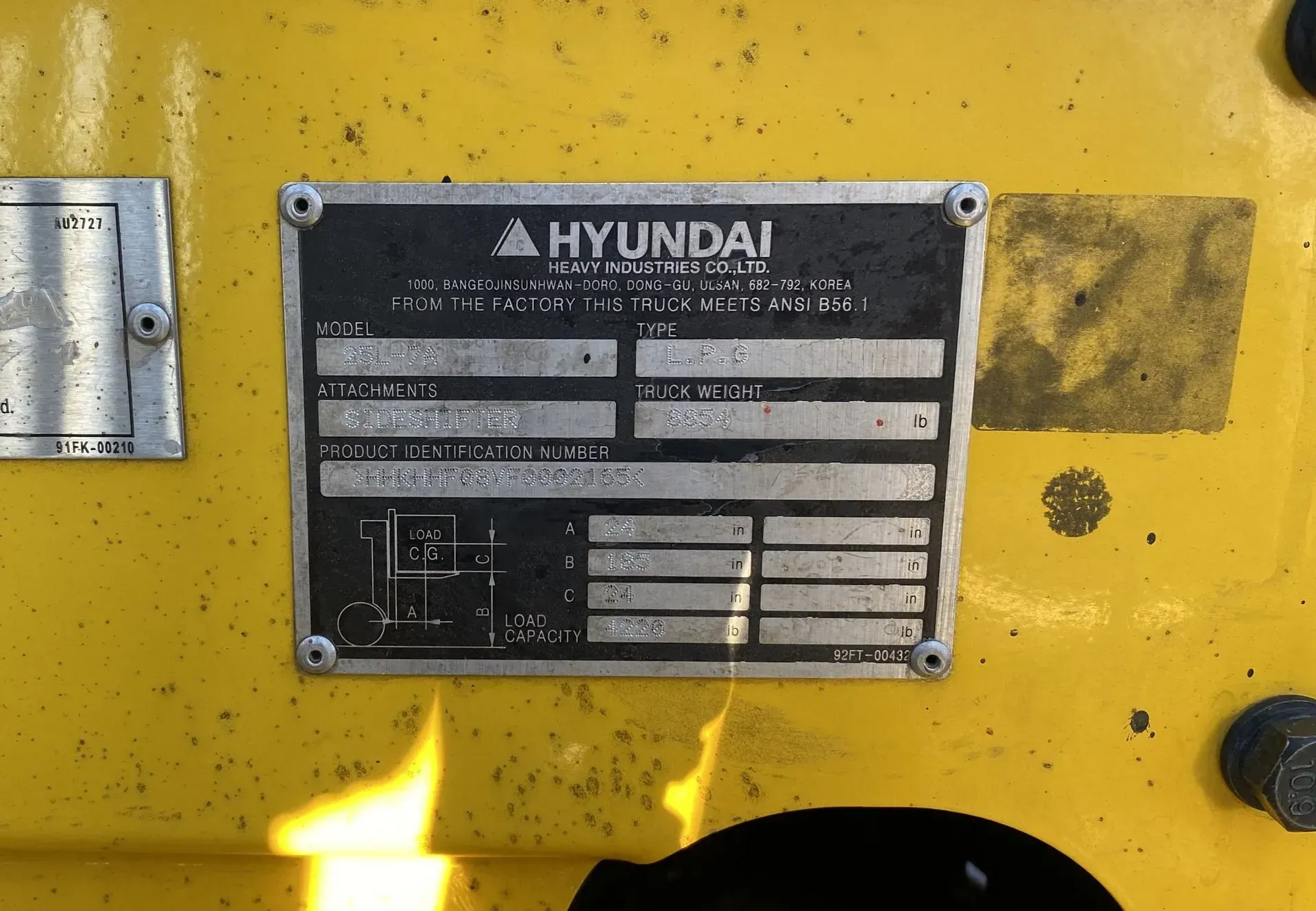 Black Hyundai equipment plate with text and diagrams, mounted on yellow machine.